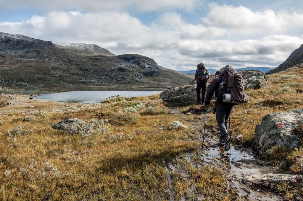 Adventurous hikers explore the scenic Vålådalen landscape in Sweden during fall.